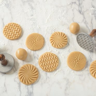 Raw cookie dough stamped with Nordic Ware geometric cookie stamps showing triangle, hexagon, and diamond patterns