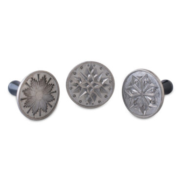 Three Nordic Ware cookie stamps with blue wooden handles and aluminum pressing surfaces, featuring star and celestial designs