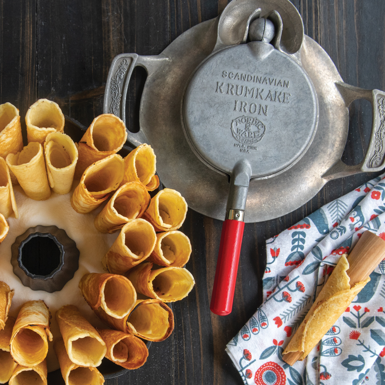 Overhead image of Nordic Ware's Krumkake Iron with rolled krumkake in scene