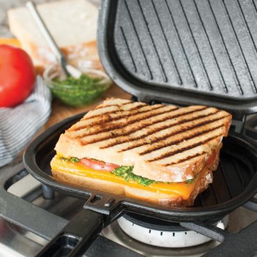 Nordic Ware aluminum stovetop sandwich grill press, open hinged design with grilled panini sandwich inside