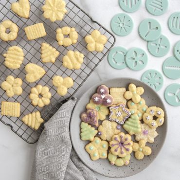 Assorted decorated spritz cookies in star, flower, and spiral shapes with colorful icing and sprinkles