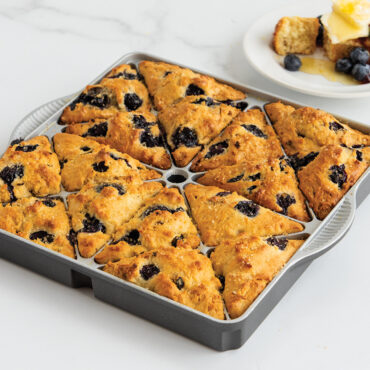 Six golden mini scones with blueberries baked in Nordic Ware aluminum mini scone pan with triangular wells