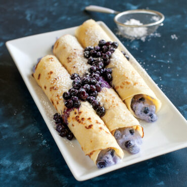 Nordic Ware steel crepe pan with golden blueberry crepes, thin and delicately folded, dark cooking surface