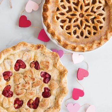 Two baked pies with Nordic Ware lattice hearts pie cutter designs - one with heart cutouts, one with lattice pattern