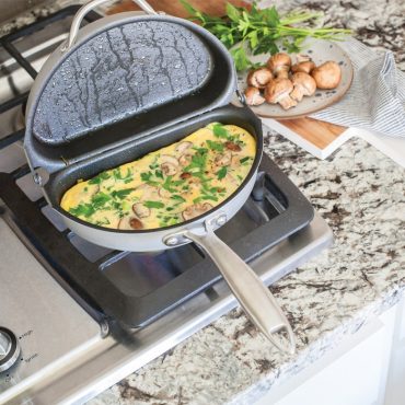 Nordic Ware aluminum frittata pan with cooked egg dish containing vegetables, golden brown surface, dual-handled cookware