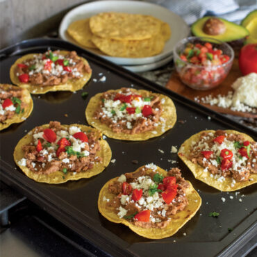Grilled meat and vegetable tostadas cooking on Nordic Ware aluminum two-burner reversible griddle on stovetop