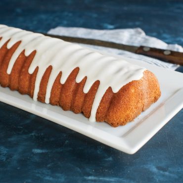 Nordic Ware aluminum loaf pan with almond-shaped bottom design, natural silver finish, baked golden almond cake