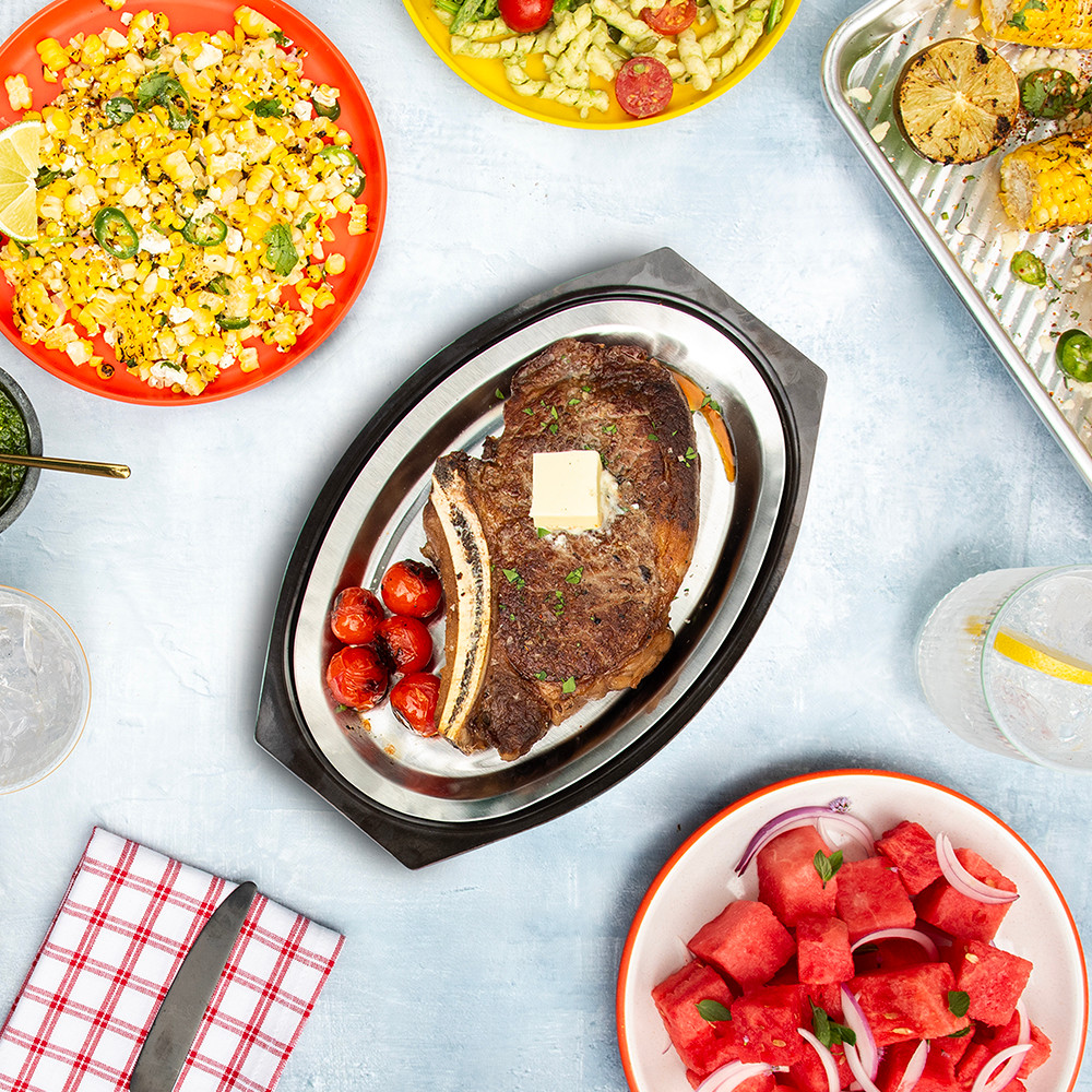 Image of top-rated sizzling server with grilled steak and other summer grilled foods in summer table scene