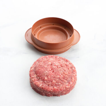 Nordic Ware aluminum stuffed burger maker with formed raw beef patty showing filling pocket