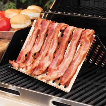 Raw bacon strips arranged on Nordic Ware aluminum grill tent with perforated surface on outdoor grill grates