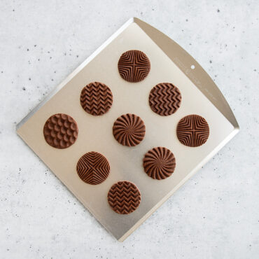 Nordic Ware aluminum cookie sheet with golden-brown chocolate chip cookies arranged in rows