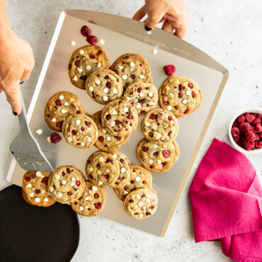 Nordic Ware aluminum cookie sheet with golden brown baked cookies arranged on natural silver surface