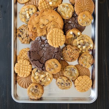 Variety of baked cookies including chocolate chip and oatmeal on Nordic Ware aluminum half sheet pan