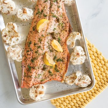 Herb-crusted salmon with lemon slices and roasted cauliflower on Nordic Ware aluminum sheet pan