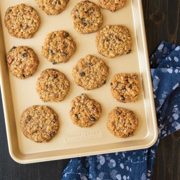 Golden oatmeal cookies with chocolate chips on Nordic Ware nonstick jelly roll baking sheet, natural aluminum