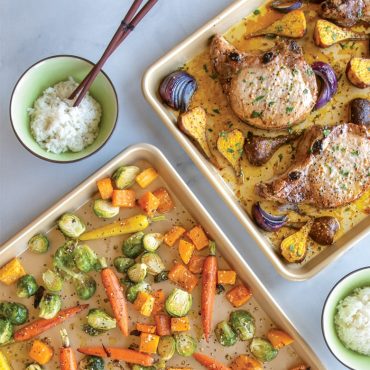 Two Nordic Ware aluminum half sheet pans with roasted vegetables and pork chops, golden brown finish