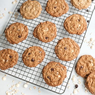 Golden baked chocolate chip cookies cooling on Nordic Ware nonstick grid rack over aluminum half sheet pan