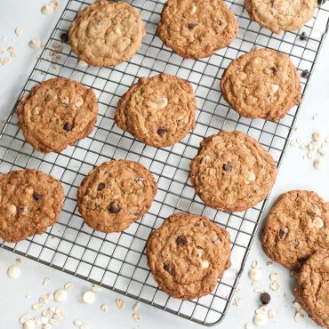 Golden brown oatmeal cookies cooling on Nordic Ware wire grid rack, evenly spaced with scattered oats