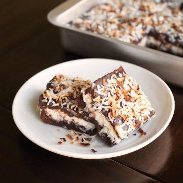 Chocolate brownies baked in Nordic Ware aluminum rectangular baker, two squares plated beside pan