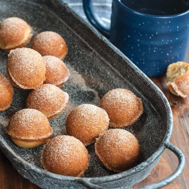 Nordic Ware cast aluminum donut hole pan with golden baked donut holes dusted with powdered sugar