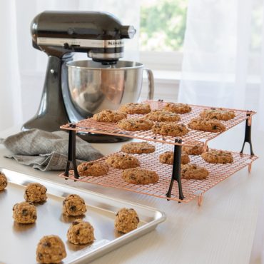 Nordic Ware stackable cooling grids with golden baked cookies, black legs, beside stand mixer and sheet pan