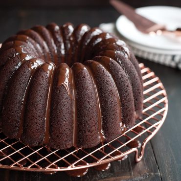 Chocolate bundt cake with glossy glaze on Nordic Ware round copper cooling grid, showing fluted ridges