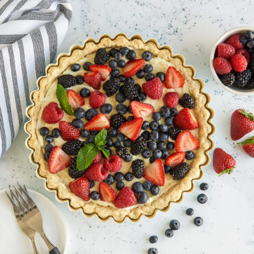 Golden baked tart filled with mixed berries in Nordic Ware fluted quiche pan with scalloped edges