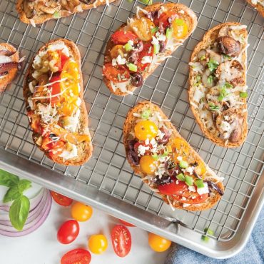 Colorful topped bruschetta on Nordic Ware wire cooling grid over aluminum sheet pan, golden toasted bread