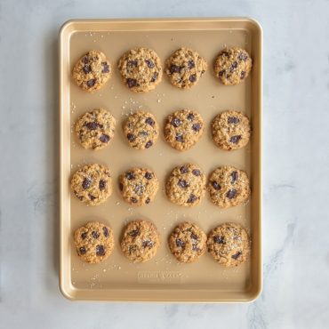 Sixteen golden chocolate chip cookies arranged in rows on Nordic Ware nonstick big sheet baking pan