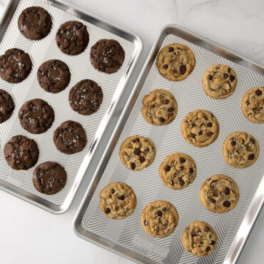 Two Nordic Ware Prism aluminum sheet pans with baked cookies - chocolate on left, chocolate chip on right