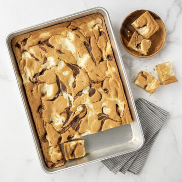 Golden brown chocolate chip blondies in Nordic Ware aluminum high-sided sheet cake pan, cut into squares