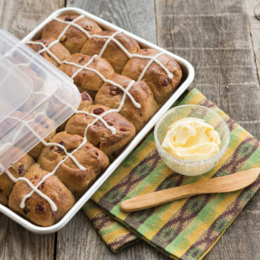 Nordic Ware aluminum quarter sheet baking pan with clear plastic storage lid, containing golden dinner rolls