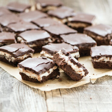 Golden marshmallow layer bars with chocolate chips cut into squares on parchment paper from Nordic Ware cake pan.
