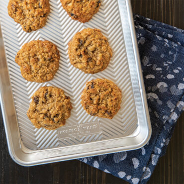 Nordic Ware aluminum quarter sheet pan with baked golden cookies, rectangular with raised rim, natural finish