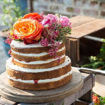 Three-layer vanilla cake with white frosting and fresh flowers, baked using Nordic Ware round cake pans