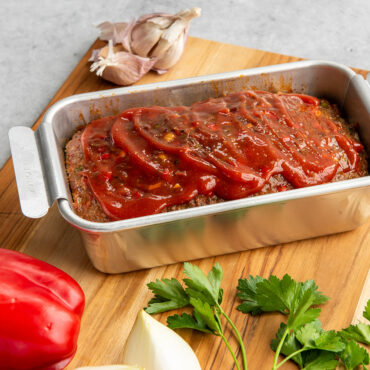 Nordic Ware aluminum meatloaf pan with glazed baked meatloaf, natural finish with white handles