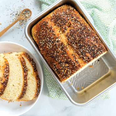 Golden brioche loaf baked in Nordic Ware Prism aluminum loaf pan with geometric ridged design, sliced pieces arranged on white plate