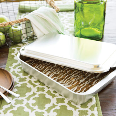 Nordic Ware aluminum 9x13 covered baking pan with metal lid partially open, containing apple streusel cake