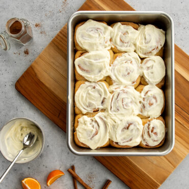 Nordic Ware aluminum rectangular cake pan with 12 frosted cinnamon rolls, natural finish, 9x13 inch