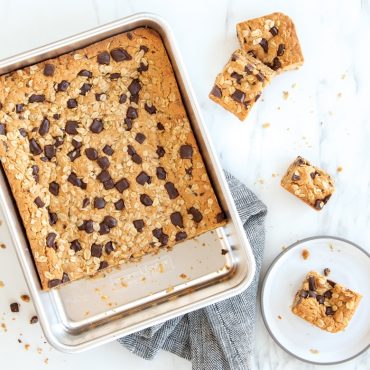 Nordic Ware aluminum 9x13 rectangular cake pan with golden oatmeal chocolate chip bars, cut pieces on white plate