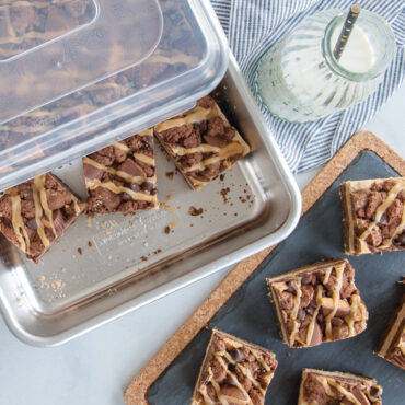 Clear storage lid covering Nordic Ware 9x13 aluminum pan filled with chocolate brownies cut in squares