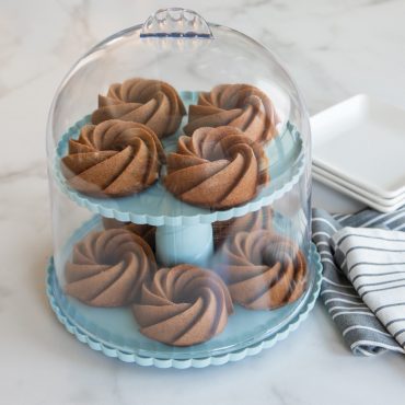 Nordic Ware aluminum 2-tiered dessert stand with clear dome lid, silver finish, displaying elegant serving design