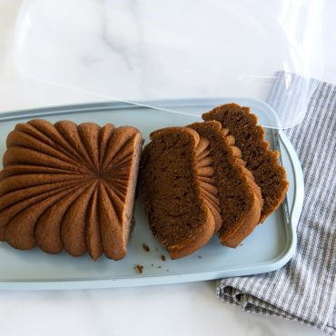 Sliced banana bread on Nordic Ware white plastic loaf cake keeper with clear lid, rectangular storage container