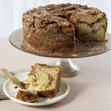 Golden tube cake with one slice cut, baked in Nordic Ware aluminum tube pan showing tall round shape