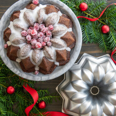 Chocolate bundt cake with white glaze and sugared cranberries in Nordic Ware aluminum Vintage Star pan