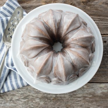 Golden bundt cake with white glaze baked in Nordic Ware Fleur-de-Lis pan, showing fluted petal design