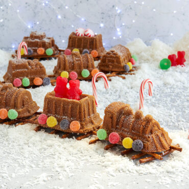 Decorated train-shaped cake with colorful candies on pretzel track, baked in Nordic Ware train cake pan