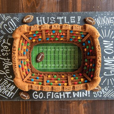 Football-shaped bundt cake from Nordic Ware Stadium pan with candy footballs and colorful sprinkles as decoration