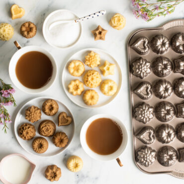 mini bundt teacakes on white small plates with cups of coffee, bowl of sugar, and pan