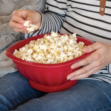 Person holding Nordic Ware red Pro Pop microwave popcorn popper filled with fresh white popcorn